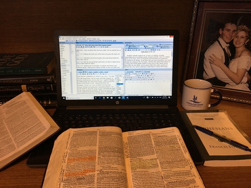photo of a bible on a desk in front of a laptop